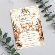 Christmas and Mistletoe invitation displayed on a pale blue background with pink floral accents and decorative greenery. The printable design features evergreen branches, red berries, and traditional vintage holiday details.