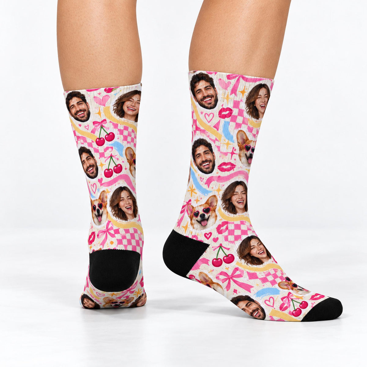 Custom printed crew socks shown from different angles against a white studio background. All-over personalized face pattern features human portraits, a corgi, pink hearts, cherries, bows, and contrasting black heels and toes.