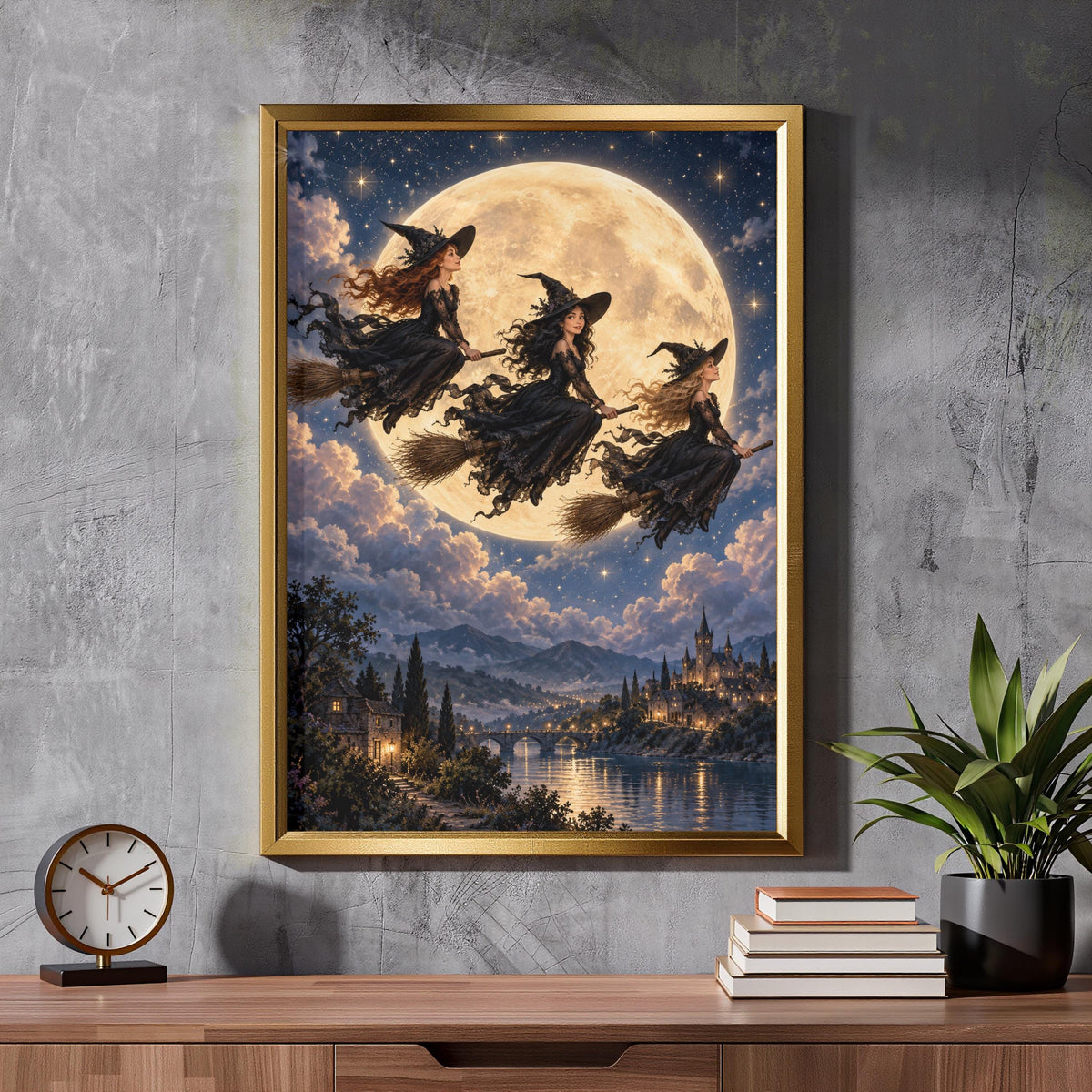 Framed moonlit witch poster resting on a wooden cabinet beside a potted plant. The artwork features three witches on broomsticks, a golden full moon, blue night sky, and fantasy castle scenery.