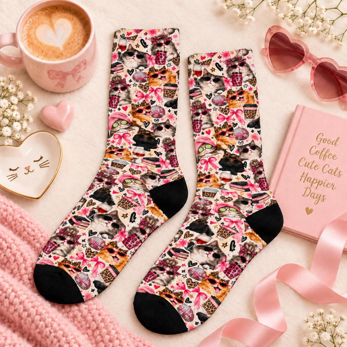 Cute cat socks displayed flat on a soft cream background with pink accessories, a coffee mug, heart-shaped sunglasses, and flowers. Colorful all-over print features fashionable cats, pink ribbons, and girly retro illustrations.