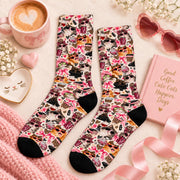 Cute cat socks displayed flat on a soft cream background with pink accessories, a coffee mug, heart-shaped sunglasses, and flowers. Colorful all-over print features fashionable cats, pink ribbons, and girly retro illustrations.