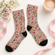 Vintage western crew socks arranged flat on a cream background with pink ribbon, delicate flowers, and a coffee mug. Colorful all-over pattern showcases cowboy boots, horseshoes, cactus illustrations, and pink bows.