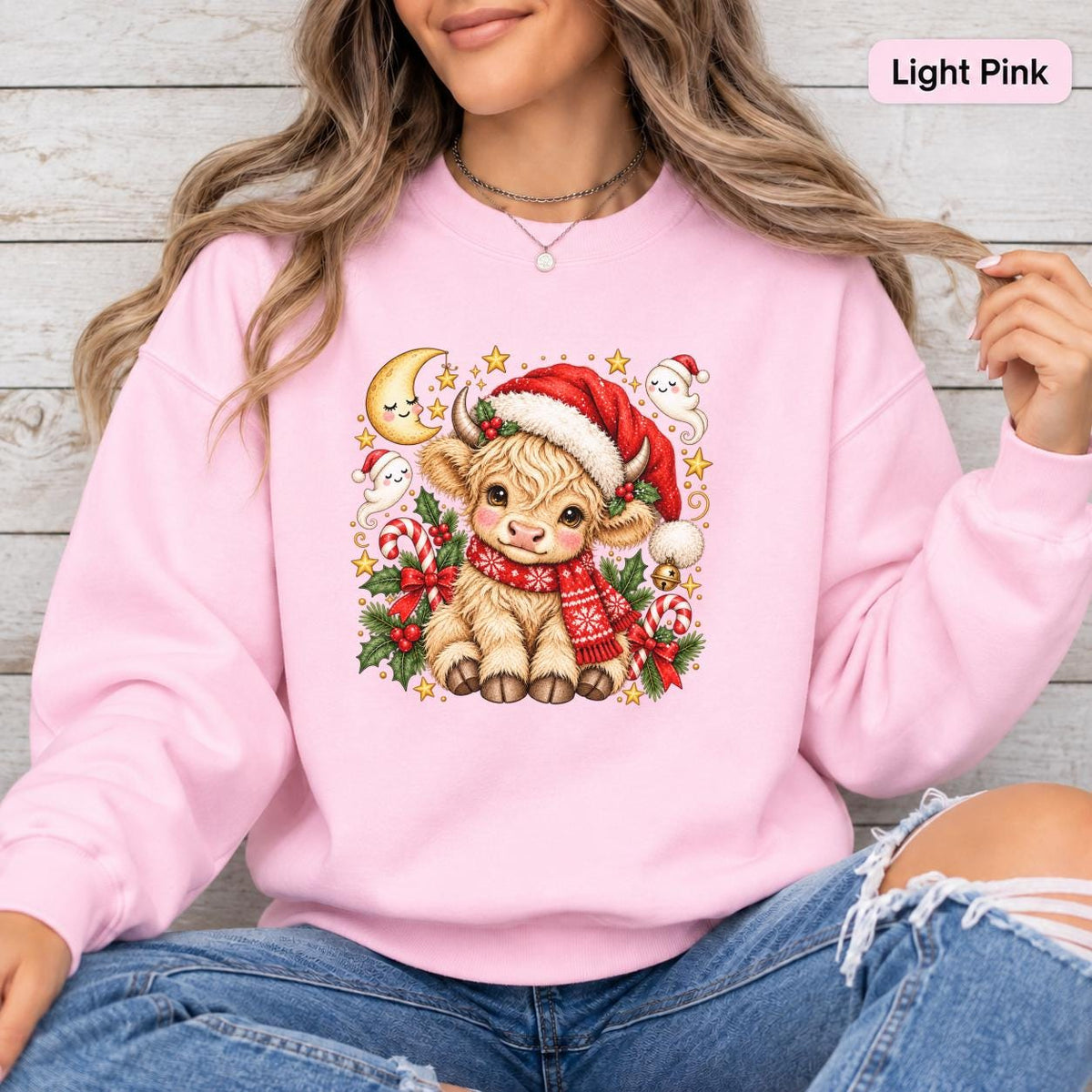 Light Pink Gildan 18000 sweatshirt featuring a cute Christmas Highland cow in a Santa hat and red scarf surrounded by candy canes, holly, stars, and festive greenery.