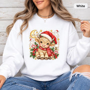 White Gildan 18000 crewneck displaying the holiday Highland cow graphic with bright red, green, gold, and cream Christmas details.