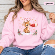 Light Pink Gildan 18000 sweatshirt featuring a cute baby reindeer with a red mitten nose boop, snowflakes, stars, evergreen branches, and festive winter details.