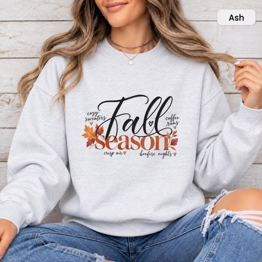Ash Gildan 18000 crewneck showing the Fall Season graphic with elegant script text, warm autumn leaves, and fall-inspired phrases.