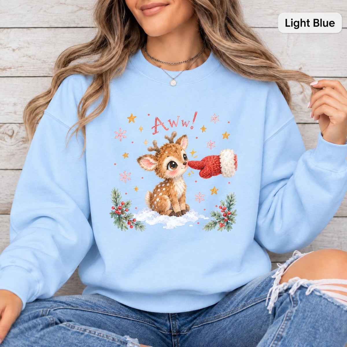 Light Blue Gildan sweatshirt featuring the sweet holiday reindeer design with a red mitten, winter greenery, berries, snowflakes, and stars.