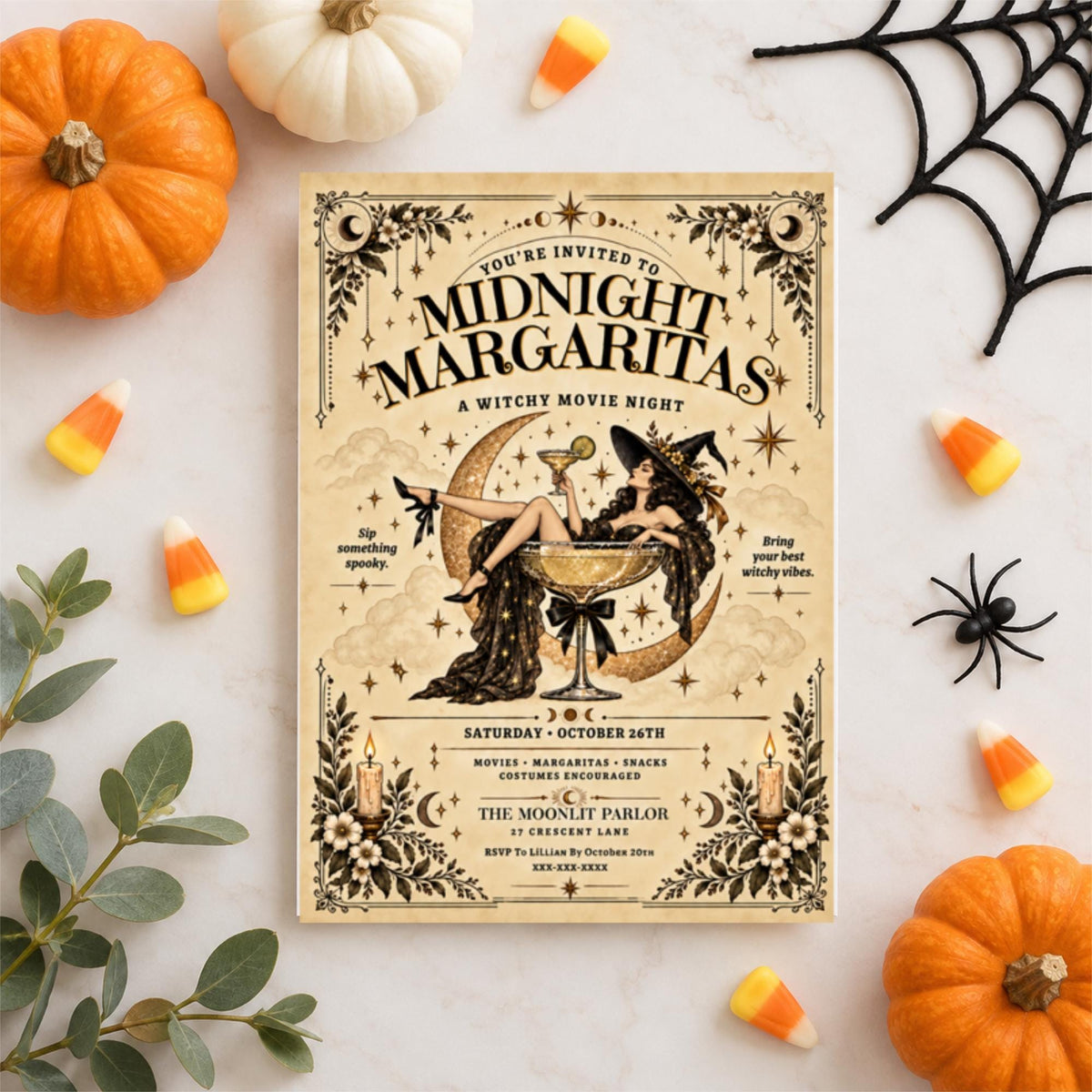 Printable Midnight Margaritas invitation displayed on a pale background with miniature pumpkins, candy corn, black spiderweb, and decorative spider. The cream and black vintage artwork features a witch, crescent moon, and cocktail glass.