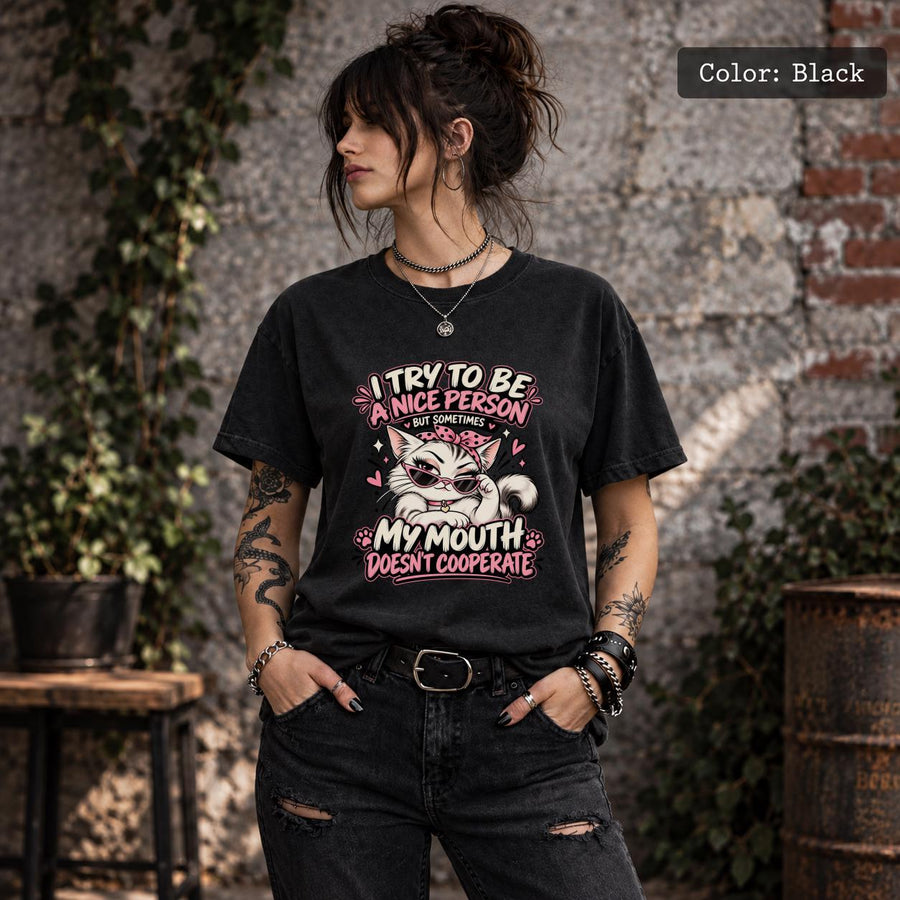 Black Comfort Colors 1717 T-shirt featuring a sassy white cat in sunglasses with pink accents and the quote “I Try to Be a Nice Person, But Sometimes My Mouth Doesn’t Cooperate.”
