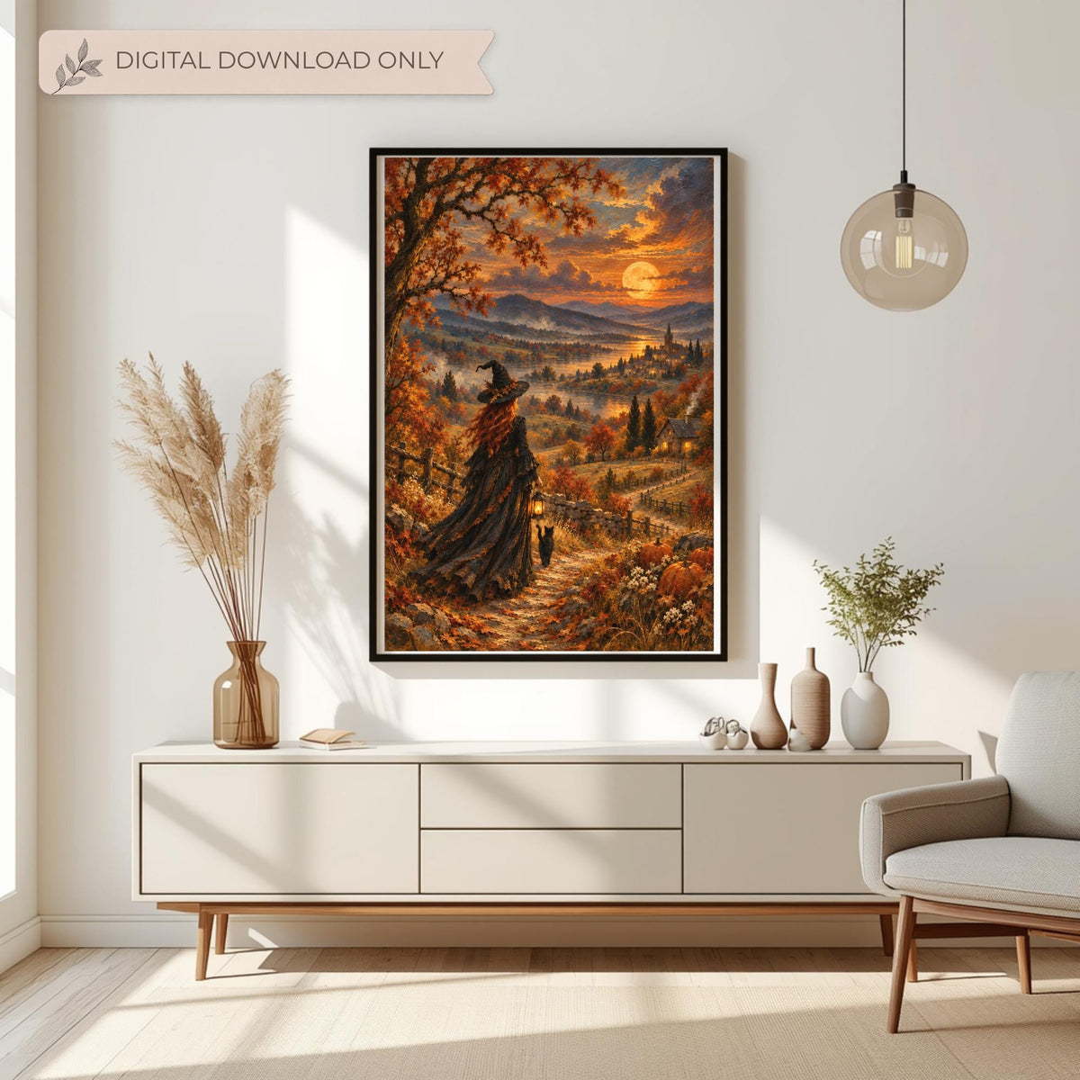 Mystical autumn witch wall art displayed in a black frame above a cream console table in a bright neutral living room. The vintage-inspired landscape painting features a red-haired witch walking with her black cat and glowing lantern beneath a golden harvest moon, surrounded by colourful fall foliage, pumpkins, and a distant village. A banner reads Digital Download Only, indicating this is printable wall art with no physical item shipped.