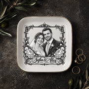 Personalized wedding jewelry dish featuring a black-and-white couple portrait, ornate floral frame, custom names, and wedding year on a square ceramic dish with gold trim.