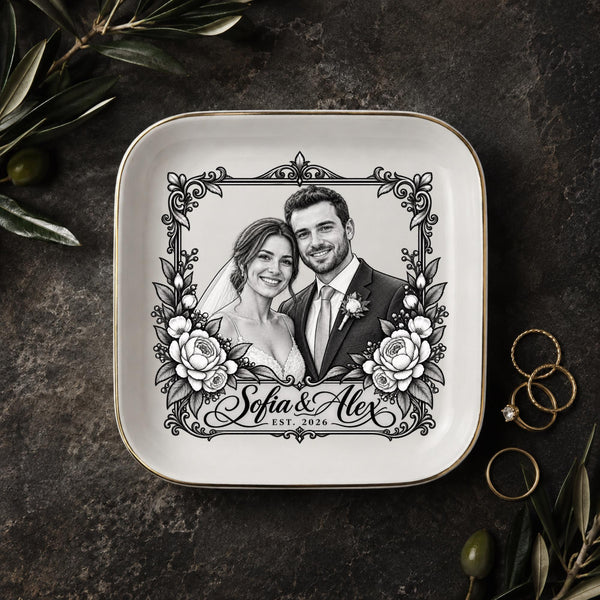 Personalized wedding jewelry dish featuring a black-and-white couple portrait, ornate floral frame, custom names, and wedding year on a square ceramic dish with gold trim.