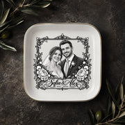 Personalized couple jewelry dish displayed on a dark elegant surface with greenery, featuring a custom wedding portrait and ornate vintage-style border.
