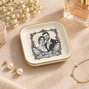 Custom wedding jewelry dish displayed with perfume and delicate accessories on a warm neutral surface, featuring a personalized couple portrait and vintage floral border.