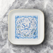 Custom couple keepsake dish shown on a soft neutral fabric background with blue botanical artwork, bows, personalized initials, and gold edging.