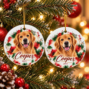 Two matching round ceramic dog ornaments displayed on a Christmas tree with warm holiday lights, featuring golden retriever portraits, festive red and green watercolor artwork, and personalized names and years.