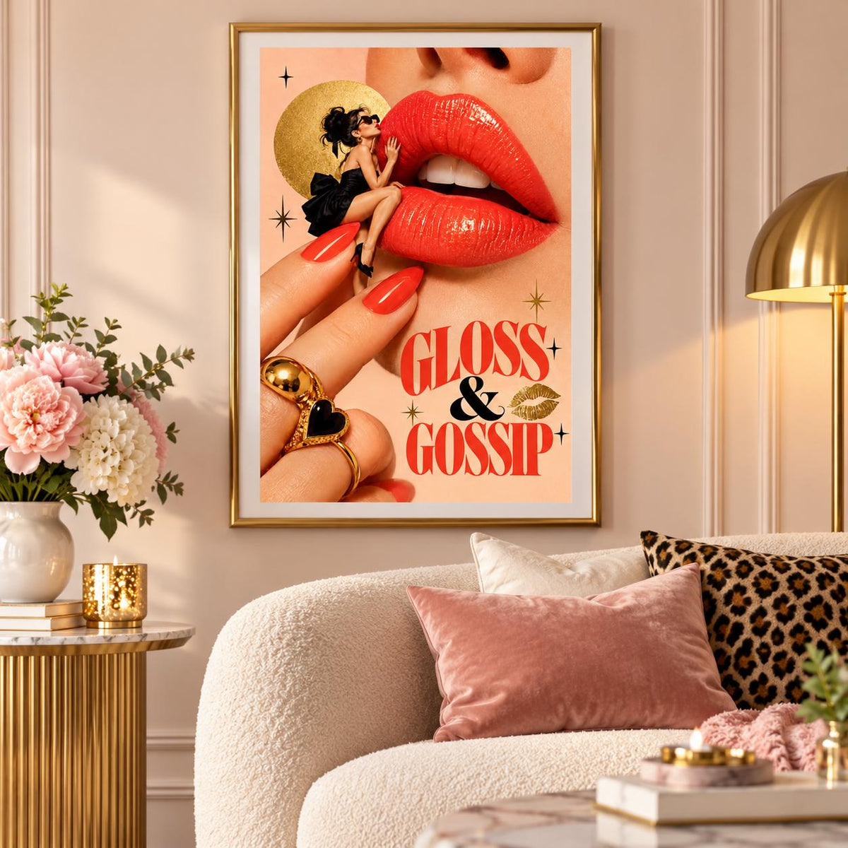 Framed retro lipstick poster hanging above a cream sofa with blush pink cushions. The colourful surreal artwork features a miniature glamorous woman sitting beside oversized red lips, with gold celestial accents and bold Gloss and Gossip lettering.