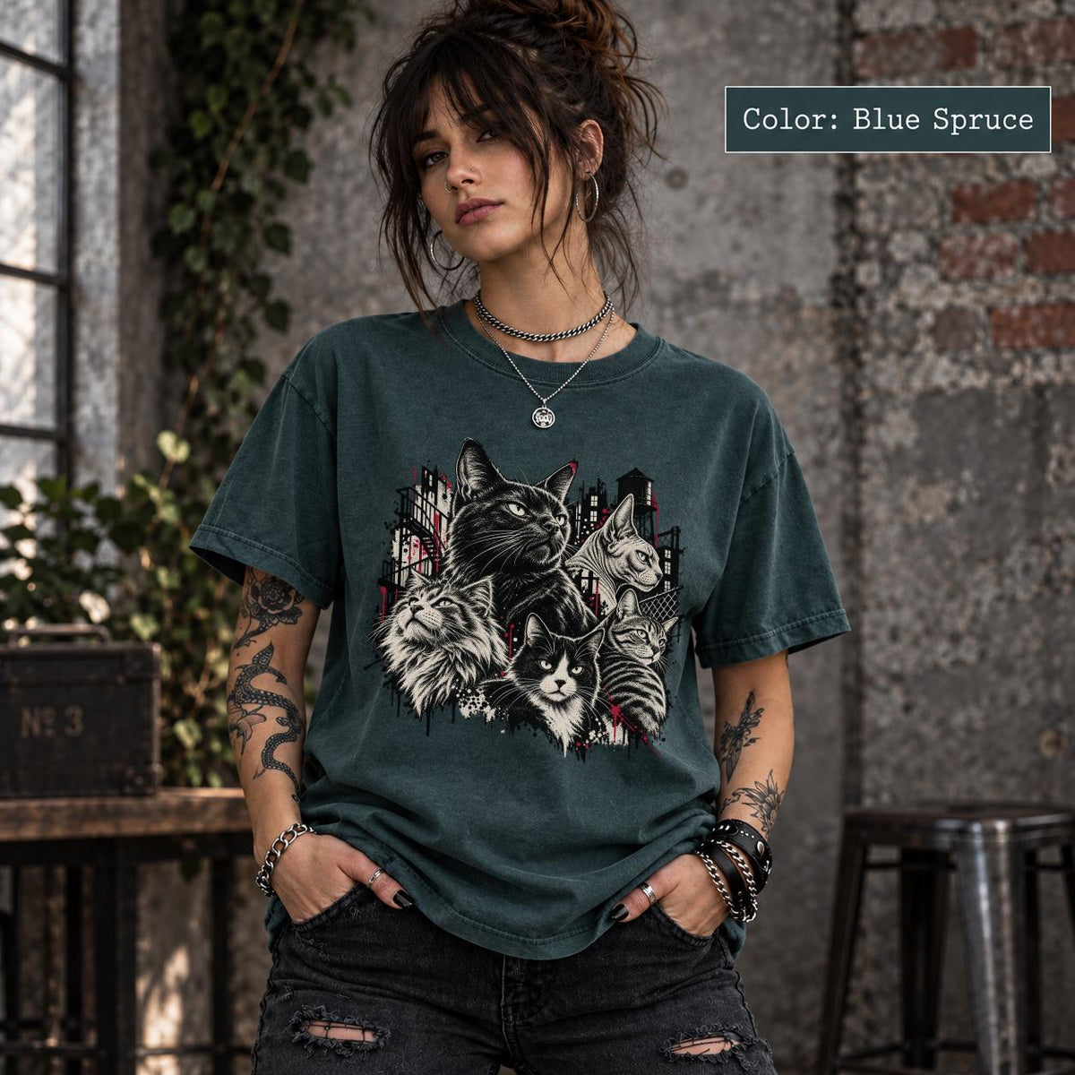 Blue Spruce Comfort Colors tee displaying the dark cat artwork with multiple illustrated cats and a moody grunge-inspired background.