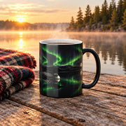 Steaming loon mug on a weathered cottage dock at sunrise, with mist on a calm lake, a pine shoreline and a plaid wool blanket beside it