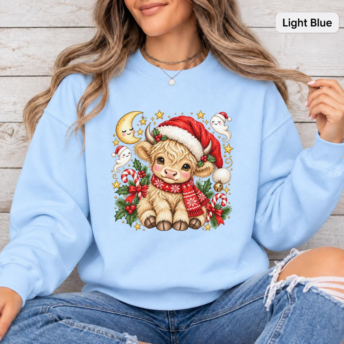 Light Blue Gildan sweatshirt featuring the adorable Highland cow Christmas design with Santa hat, scarf, candy canes, holly berries, and winter accents.
