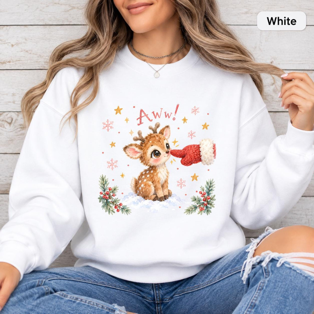 White Gildan 18000 crewneck displaying the adorable reindeer Christmas graphic with snowy accents, greenery, golden stars, and playful “Aww!” lettering.