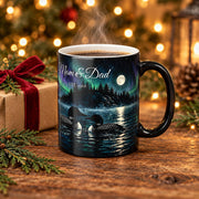 Personalized loon couple mug on a rustic table beside a wrapped Christmas gift and cedar sprigs, showing two loons under the northern lights with the example names Mom and Dad, Est. 1988, in the sky